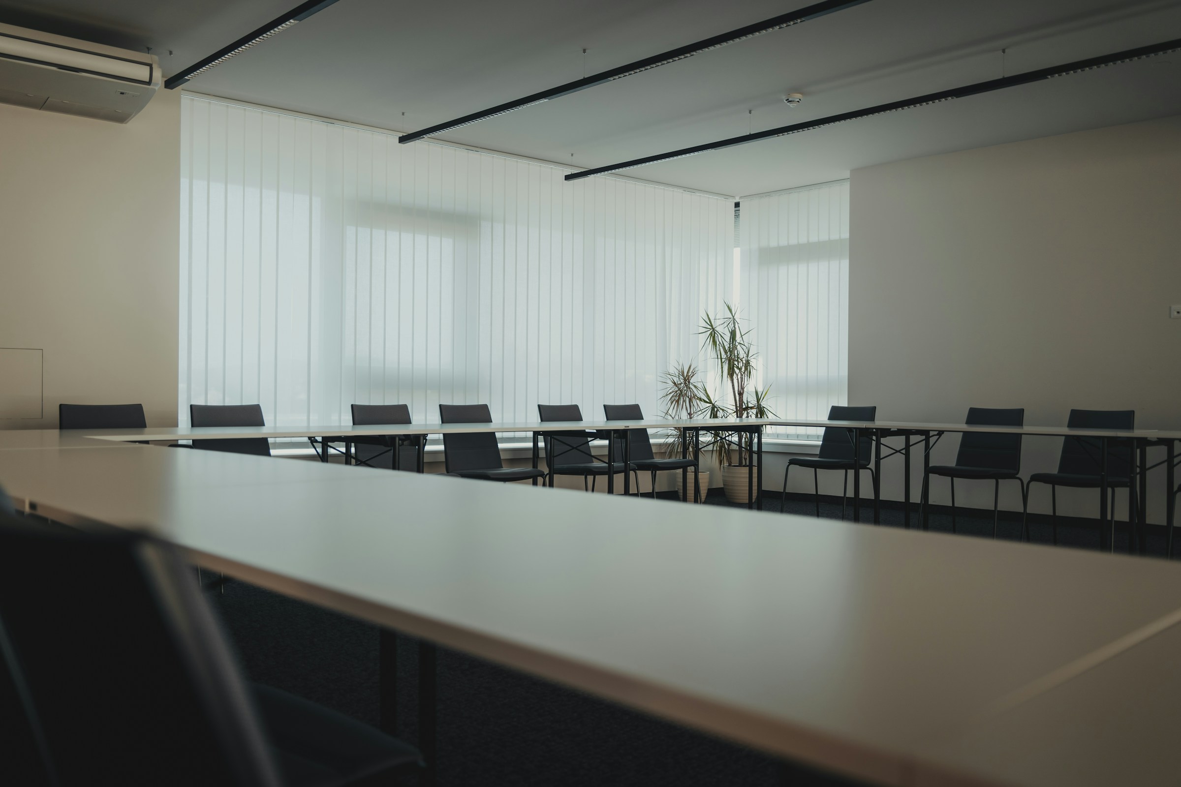 An empty meeting room with a long table, chairs down both sides and daylight from the windows