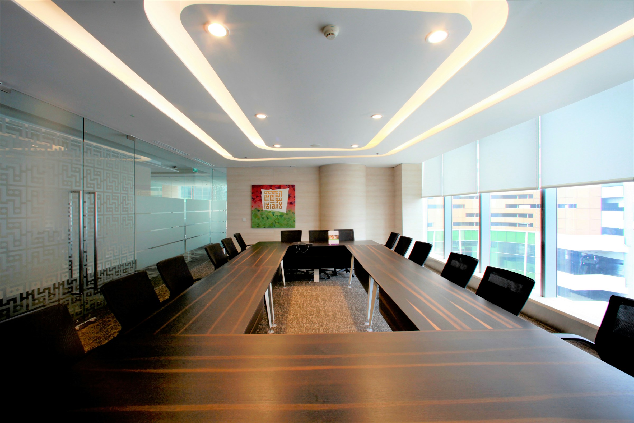 A modern conference room set up and waiting, chairs pushed in around a long table